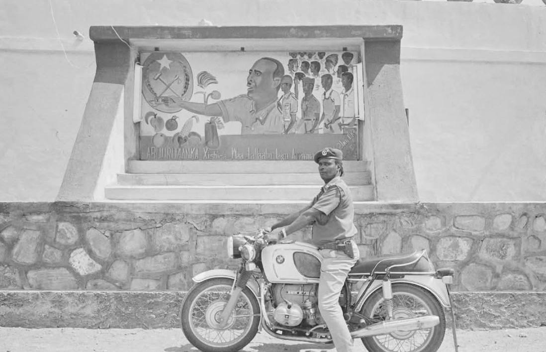 A Somali police officer beneath a portrait of Siad Barre, Mogadishu, 1977